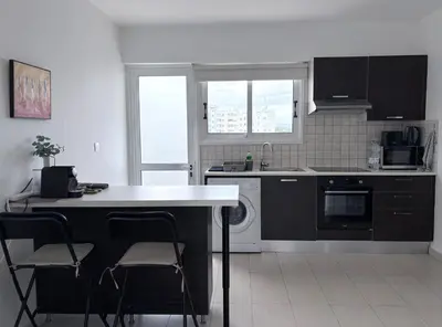 a kitchen with black cabinets and a white counter top at Cozy Central Stay with City Views in Nicosia