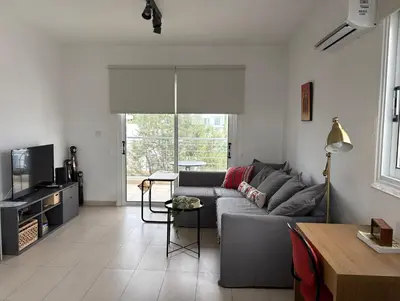 a living room with a gray couch and a tv at Cozy Central Stay with City Views in Nicosia