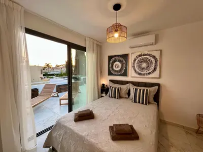 a bedroom with a large bed and a balcony at FatCow Beach Apartment Ultra in Larnaka