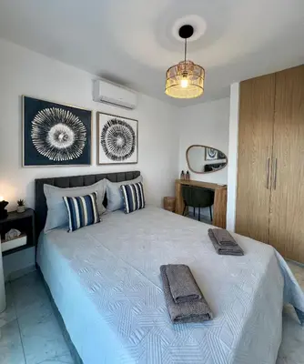 a bedroom with a large bed with two towels on it at FatCow Beach Apartment Ultra in Larnaka