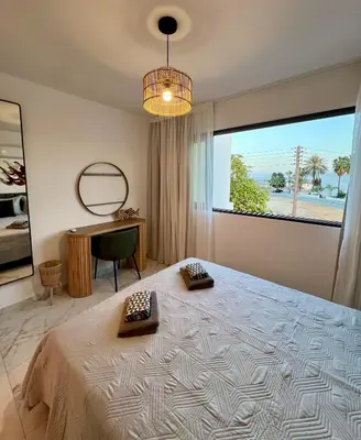 a bedroom with a bed and a desk and a window at FatCow Beach Apartment Ultra in Larnaka