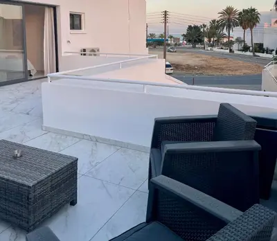 a balcony with two chairs and a table on a building at FatCow Beach Apartment Ultra in Larnaka