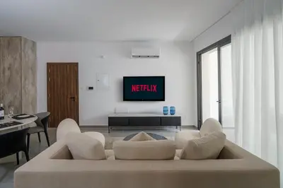 a living room with a couch and a tv on a wall at Kalamon Luxury Suite 203 w Pool and Gym in Livadhia