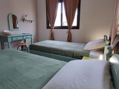 a bedroom with two beds and a table and a mirror at Anemone - walk to the beach in Paralimni