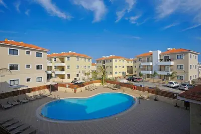 a large swimming pool in a courtyard with buildings at Anemone - walk to the beach in Paralimni