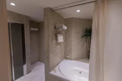 a bathroom with a shower and a tub and a sink at Iliada Beach Hotel in Protaras
