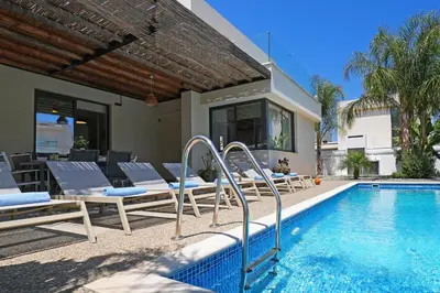 a swimming pool with lounge chairs and a house at Villa Evergreen - 3bed Bungalow large pool in Protaras