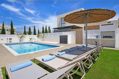 a villa with a swimming pool with chairs and an umbrella at Villa Violeta - 3bed Bungalow large pool in Protaras