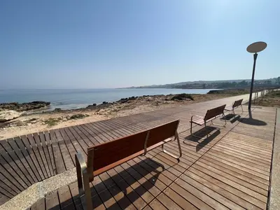 three benches sitting on a boardwalk near the water at Silver Sands Beach Hotel in Protaras