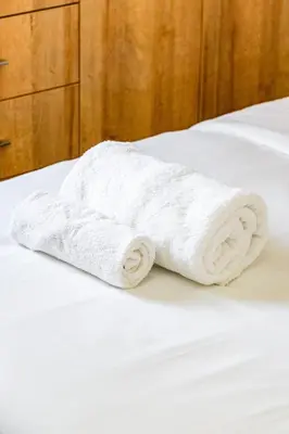 a roll of white towels sitting on a bed at Aeolis Court Apartment by Ezoria Villas in Limassol