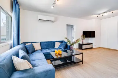 a living room with a blue couch and a table at Aeolis Court Apartment by Ezoria Villas in Limassol