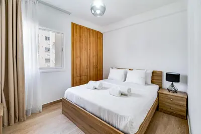 a bedroom with a bed with white sheets and a window at Aeolis Court Apartment by Ezoria Villas in Limassol