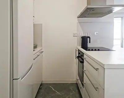a white kitchen with a stove and a refrigerator at Naxou Modern Residence By Staycom in Nicosia