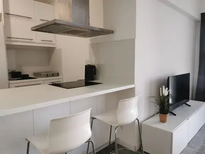 a kitchen with white chairs and a counter with a tv at Naxou Modern Residence By Staycom in Nicosia