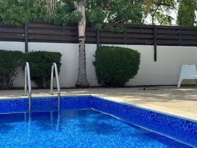 a blue swimming pool with a palm tree in the background at Sunset Villa Agia Thekla in Ayia Napa