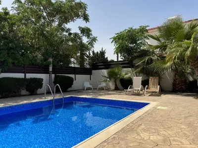a swimming pool in a yard with chairs and trees at Sunset Villa Agia Thekla in Ayia Napa