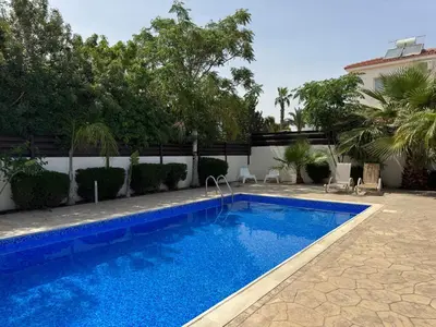 a swimming pool in a yard with trees and a building at Sunset Villa Agia Thekla in Ayia Napa