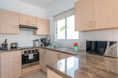 a kitchen with marble counter tops and wooden cabinets at Narcissos Bay View Villa in Protaras