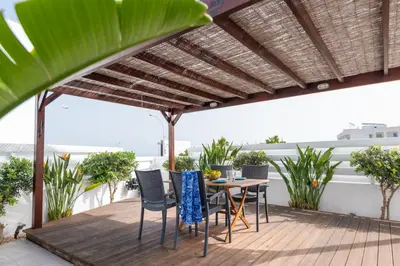 a patio with a wooden table and chairs under a pergola at Narcissos Bay View Villa in Protaras