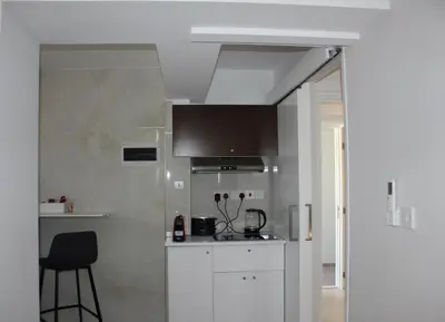 a kitchen with white cabinets and a black chair at Nicosia Central Suites in Nicosia
