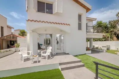 a white house with white chairs and a patio at La Casa De Louie in Ayia Napa