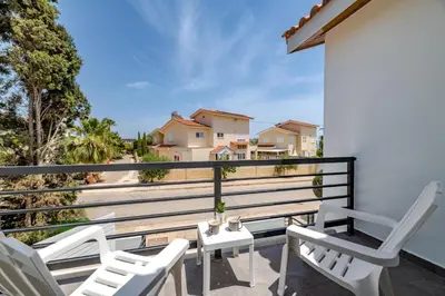 a balcony with white chairs and a view of houses at La Casa De Louie in Ayia Napa