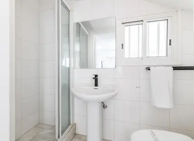 a white bathroom with a sink and a mirror at La Casa De Louie in Ayia Napa