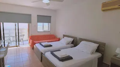 a hotel room with two beds and a balcony at STAY Nissi Heaven Studio in Ayia Napa