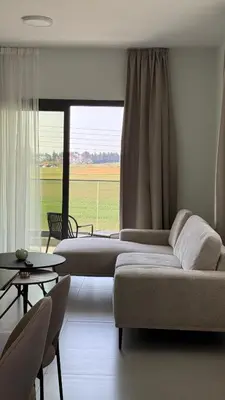 a living room with a couch and a large window at ΘΕΑ 5 Comfortable 1BR and 2BR Apartments in Mor Menekshe