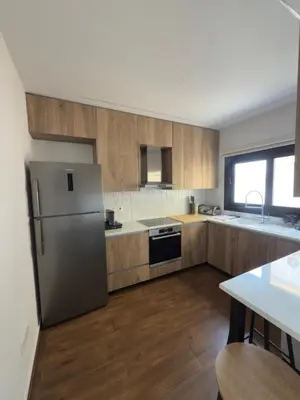 a kitchen with a stainless steel refrigerator and wooden cabinets at Stylish 2 bedroom apartment in Limassol in Limassol