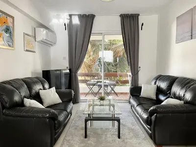a living room with black leather couches and a table at STAY Napa Dreams Apartment in Ayia Napa