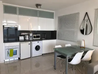 a kitchen with white cabinets and a green table and chairs at Pissouri Beach Front Apartments in Pissouri