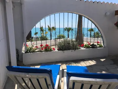 two chairs and a window with a view of the beach at Pissouri Beach Front Apartments in Pissouri