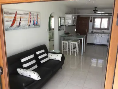 a living room with a black couch and a kitchen at Pissouri Beach Front Apartments in Pissouri