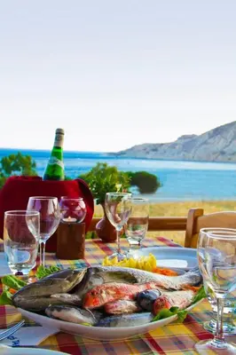 a table with a plate of fish and wine glasses at Yialos Apartments in Pissouri