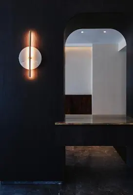 a light on a black wall with a mirror at Pendeli Resort in Platres