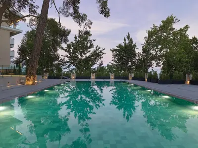 a swimming pool with green water and trees at Pendeli Resort in Platres