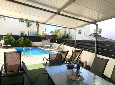 a patio with a table and chairs and a swimming pool at Athena Holiday Villa DPS01 in Protaras