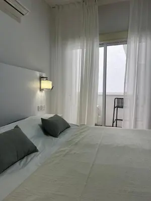 a bedroom with a large white bed with a window at The Catherine in Larnaka