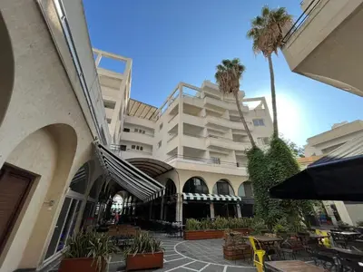 a large building with palm trees in front of it at The Catherine in Larnaka