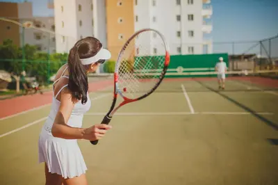 a woman holding a tennis racket on a tennis court at CAESAR RESORT İSKELE Long Beach in Vrysoules