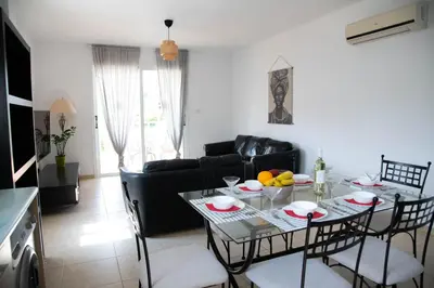 a living room with a table and a black couch at Pavilion Apt Cozy 2BR by Elysio in Paralimni