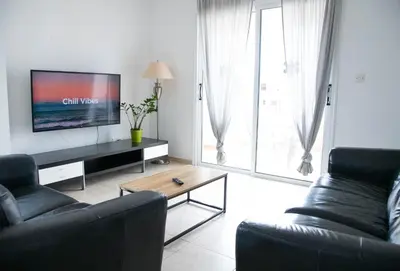a living room with a couch and a flat screen tv at Pavilion Apt Cozy 2BR by Elysio in Paralimni
