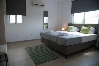 a bedroom with a large bed with green pillows at Pavilion Apt Cozy 2BR by Elysio in Paralimni