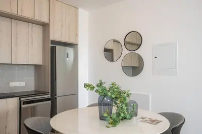 a kitchen with a table and chairs and mirrors at Kalamon Luxury Suite 202 w Pool and Gym in Larnaka