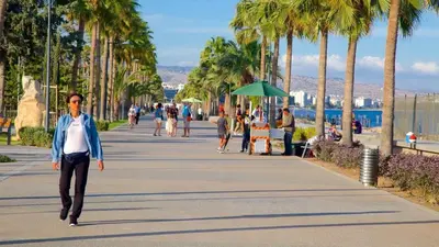 a man walking down a sidewalk with palm trees at Boutique & Brand New Prime Location Park & Beach in Limassol