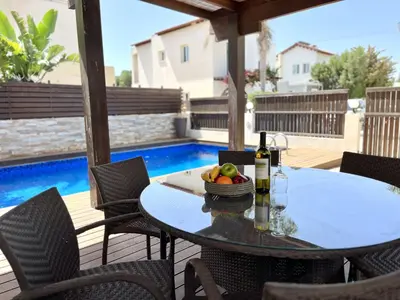 a table with a bottle of wine and fruit on a patio at STAY Thalassa Villa in Paralimni