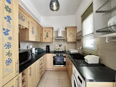 a kitchen with wooden cabinets and black counter tops at STAY Thalassa Villa in Paralimni