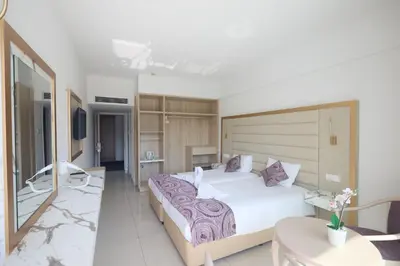 a bedroom with a large white bed and a table at Tsokkos Protaras Beach Hotel in Protaras
