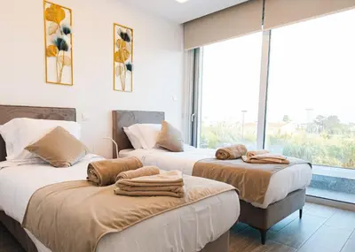 two beds in a room with a large window at Nissinest Luxury Villas in Ayia Napa